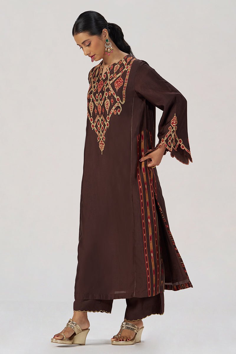 A woman modeling a dark brown kurta set with intricate red, orange, and gold embroidery on the neckline and sleeve cuffs, paired with matching brown pants, against a plain light gray studio background. | Deep Coffee Festive Co-ord Set - Ganga Fashions