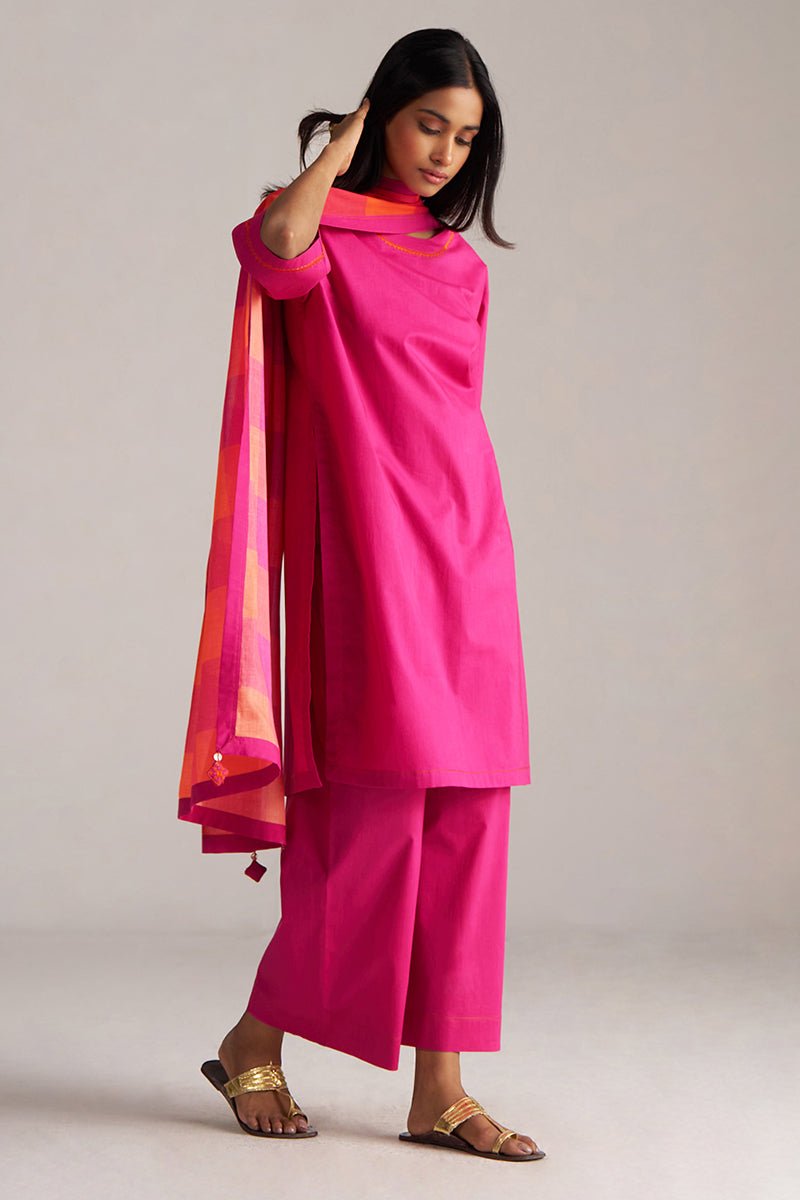 Woman wearing a bright pink traditional outfit with a colorful dupatta on a plain background | Fuchsia Solid Kurta with Mul Mul Dupatta