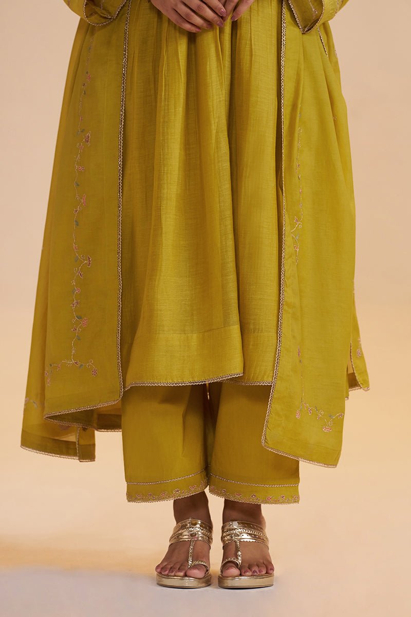 A person wearing a mustard yellow traditional outfit with matching pants and sandals, shown from the waist down against a plain beige studio background. | Lemon Curry Festive Kurta Set - Ganga Fashions