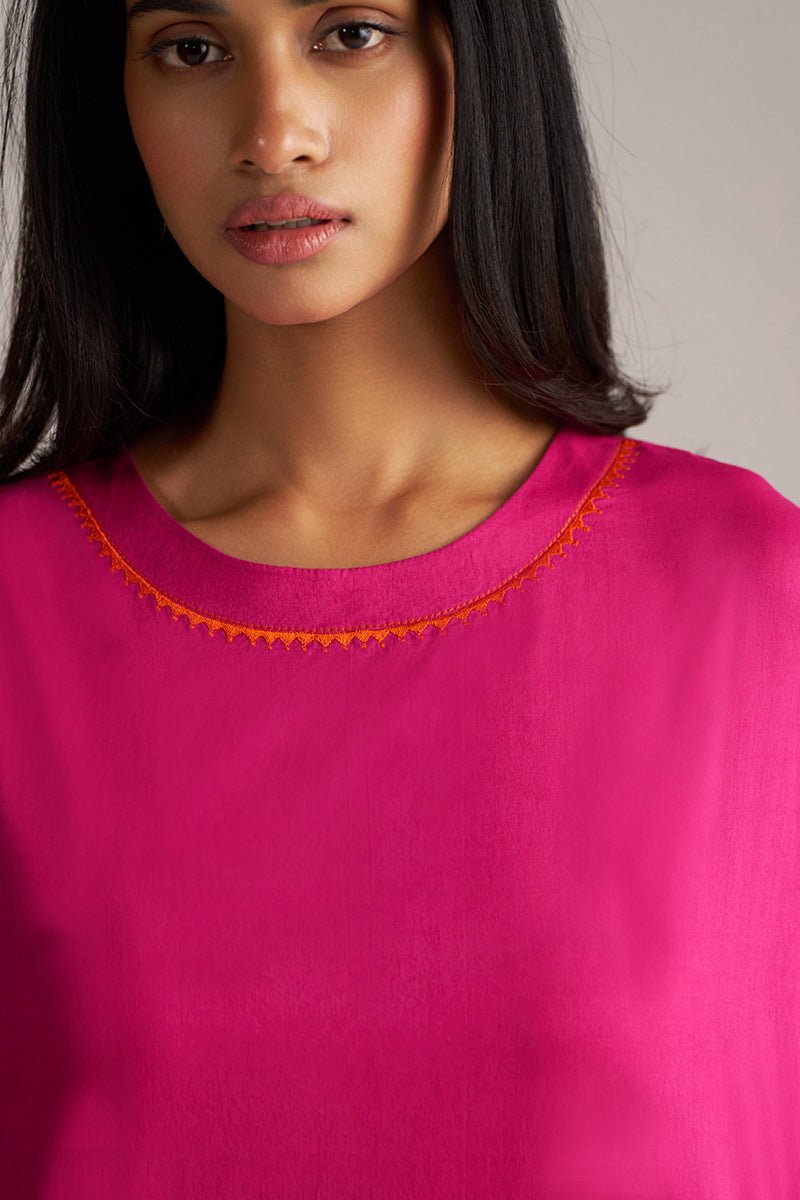 Woman wearing a bright pink top with orange trim on a plain background | Fuchsia Solid Kurta with Mul Mul Dupatta