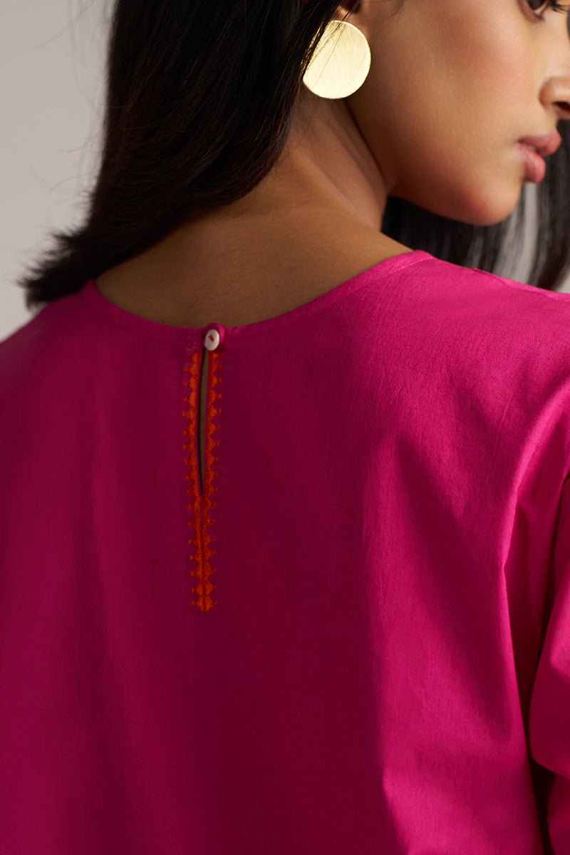 Close-up of a person wearing a bright pink top with orange embroidery details. | Fuchsia Solid Kurta with Mul Mul Dupatta