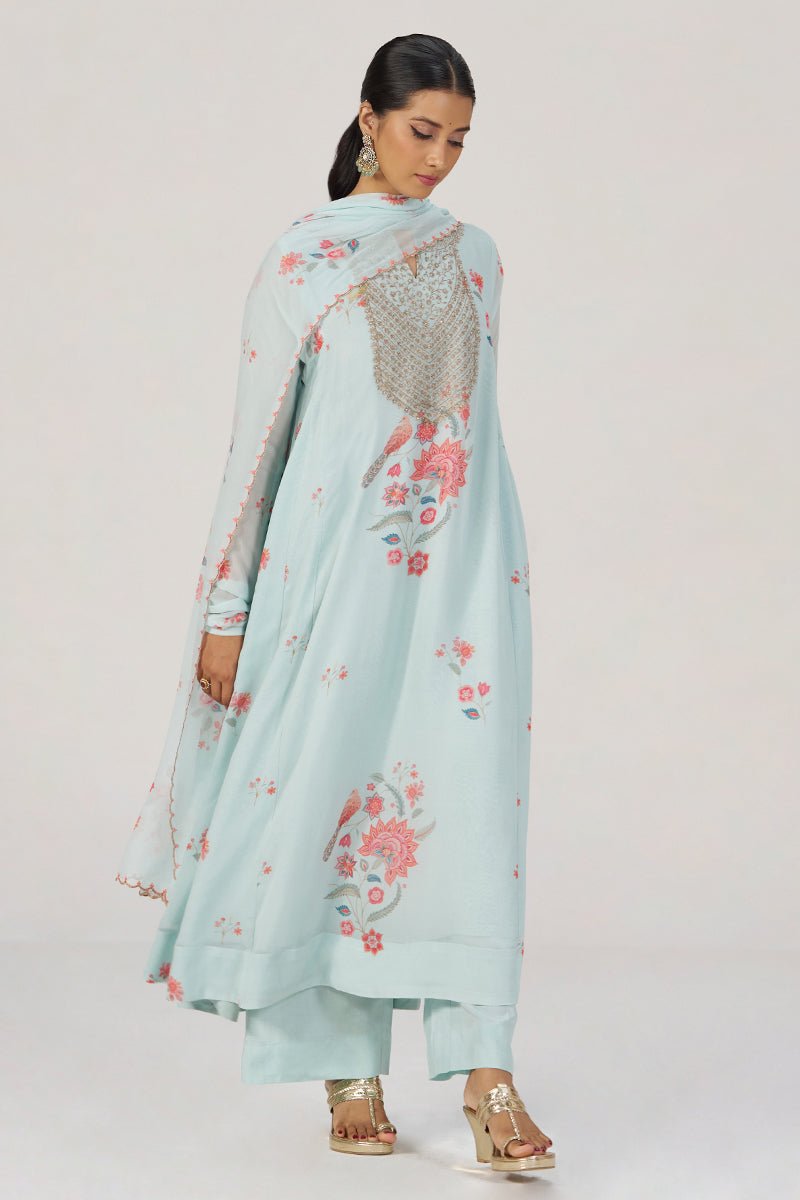 A woman modeling a light blue traditional outfit with pink floral embroidery and a matching dupatta, photographed against a plain light gray studio background. | Whispering Blue Georgette Festive Kurta Set - Ganga Fashions