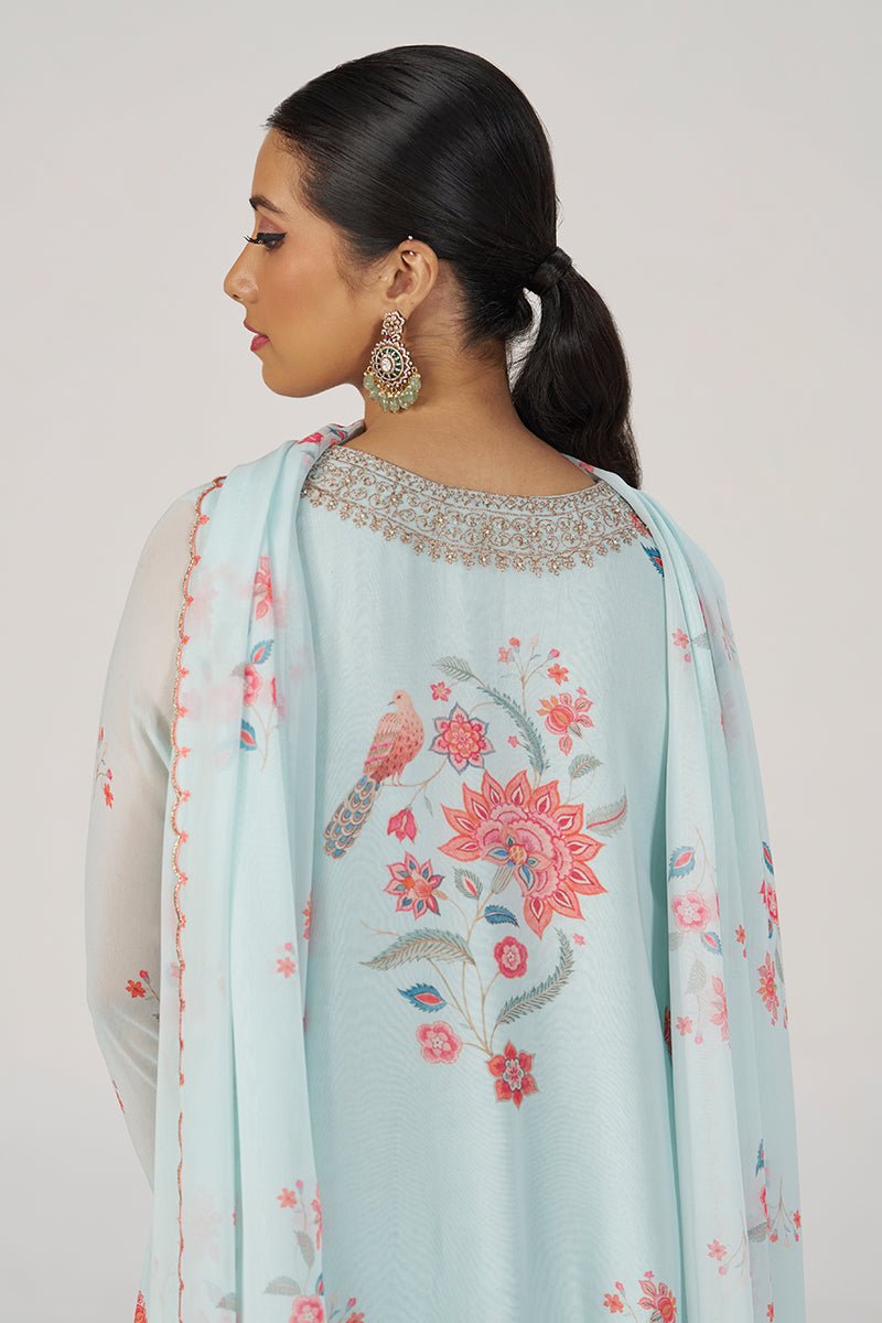 A woman shown from the back wearing a light blue traditional outfit with pink floral embroidery and a matching embroidered dupatta, against a plain light gray studio background. | Whispering Blue Georgette Festive Kurta Set - Ganga Fashions