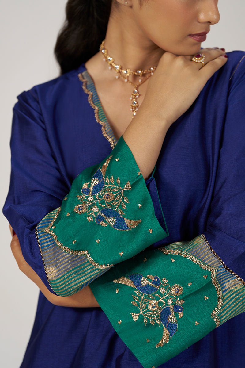 A close-up of a model wearing a royal blue kurta with a green dupatta featuring detailed gold and blue embroidery. | Space Blue Festive Kurta Set - Ganga Fashions
