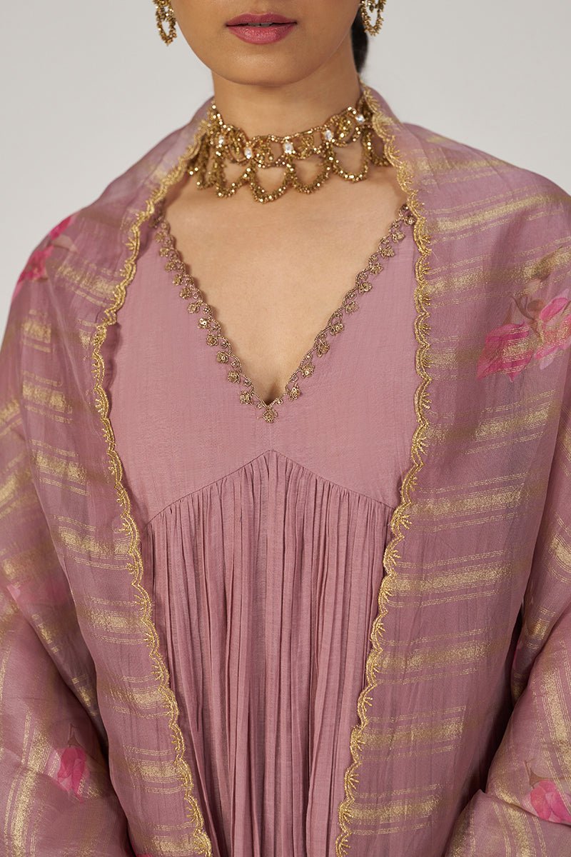 A close-up of a model wearing a dusty pink traditional outfit with a matching sheer shawl featuring gold stripes and pink floral motifs, accessorized with a chunky gold necklace. | Woodrose Chanderi Silk Festive Kurta Set - Ganga Fashions