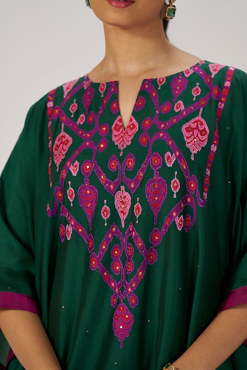 A close-up of a dark green kurta featuring intricate magenta and pink embroidery around the split neckline and chest, worn by a model. | Evergreen Silk Festive Kaftaan Set - Ganga Fashions