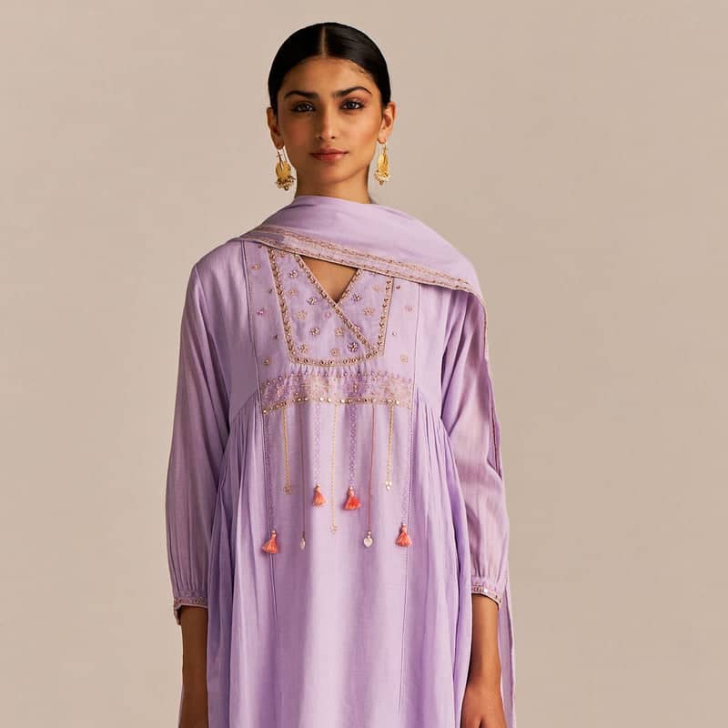 Woman wearing a light purple dress with intricate embroidery on a beige background | kahaniyaan collection by ganga fashions