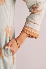Close-up of a hand wearing a Grey-Rust Mul Kurta Set on a garment with floral embroidery.