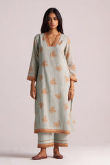 Woman wearing a Grey-Rust Mul Kurta Set with floral patterns on a plain background