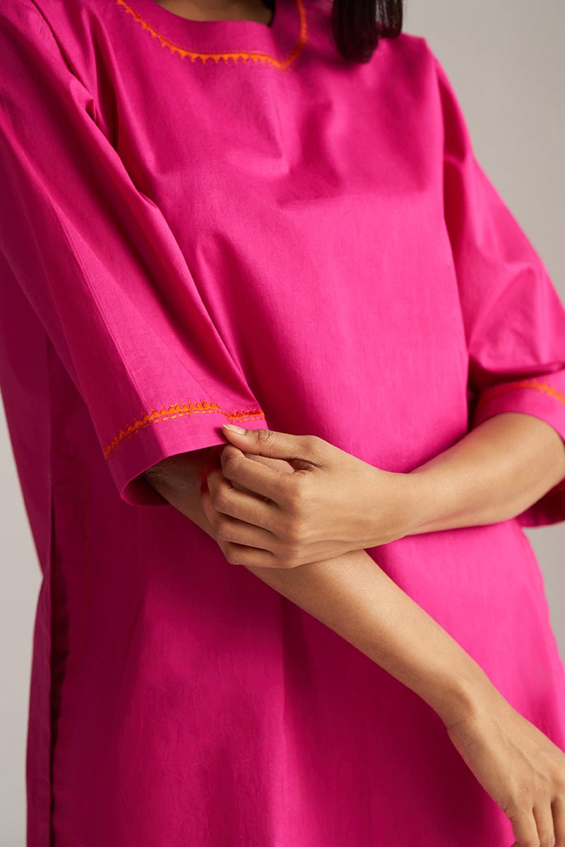Person wearing a bright pink dress with orange trim on a neutral background | Fuchsia Solid Kurta with Mul Mul Dupatta