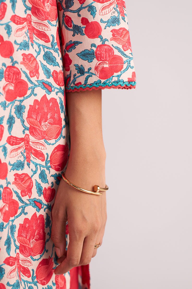 Close-up of a person wearing a Beige and Red Cotton Print Co-ord Set with a gold bracelet on a light gray background