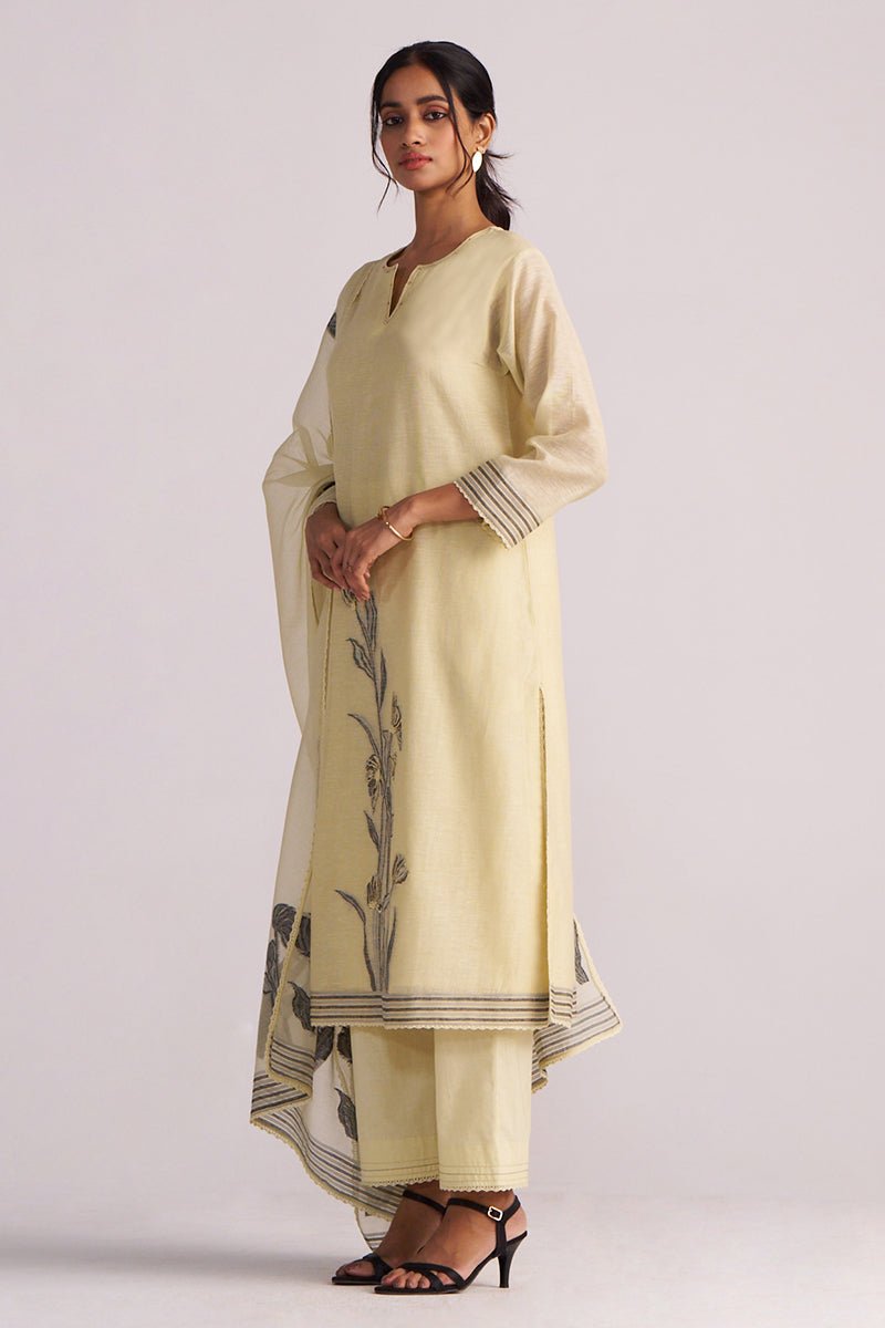 Woman wearing a Butter Yellow Chanderi Woven Kurta Set with black floral patterns on a white background