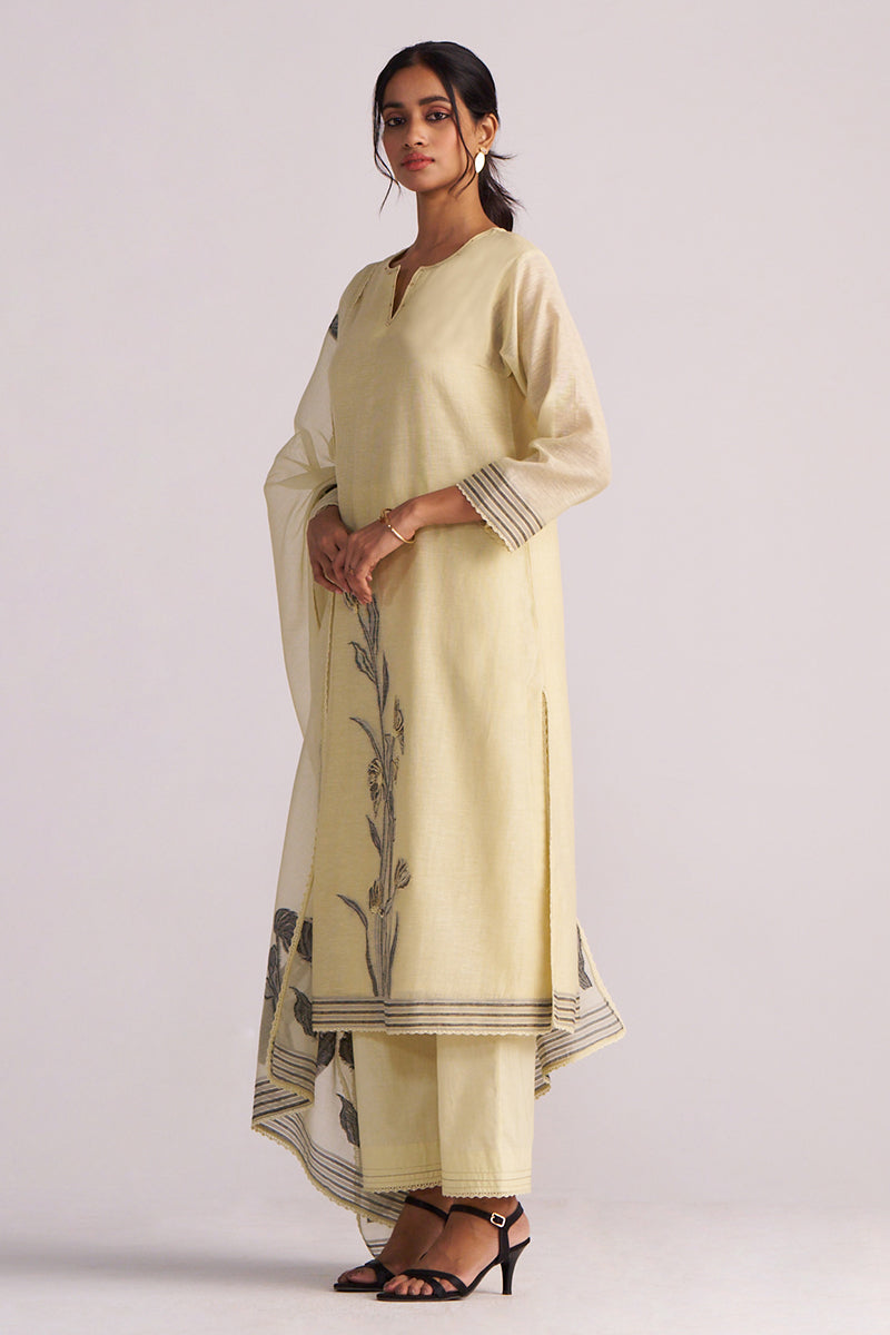 Woman wearing a Butter Yellow Chanderi Woven Kurta Set with black floral patterns on a white background