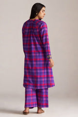 Woman wearing a purple and pink checkered outfit on a plain background