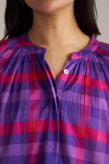 Close-up of a person wearing a purple and pink checkered shirt.