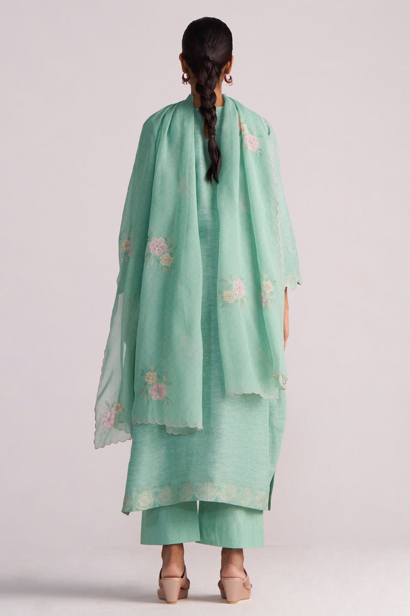 Person wearing a Dusty Jade Green Woven Silk Kurta Set with floral patterns on a plain background