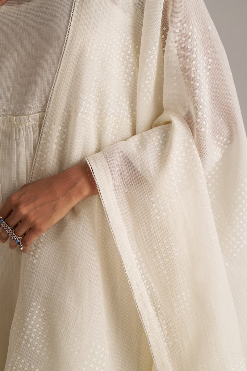 Close-up of a beige dress with a textured fabric and a hand holding a ring. | Ivory Kota Silk Kurta Set for Women