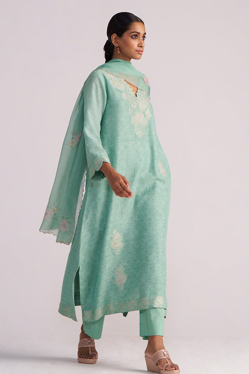 Woman wearing a Dusty Jade Green Woven Silk Kurta Set with floral patterns on a white background