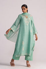 Woman wearing a Dusty Jade Green Woven Silk Kurta Set with floral patterns on a white background
