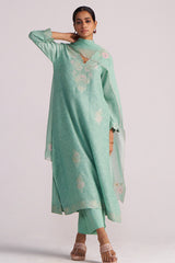 Woman wearing a Dusty Jade Green Woven Silk Kurta Set with floral patterns on a plain background