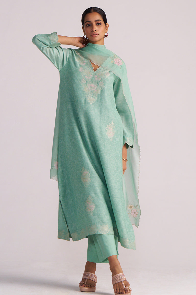 Woman wearing a Dusty Jade Green Woven Silk Kurta Set with floral patterns on a plain background
