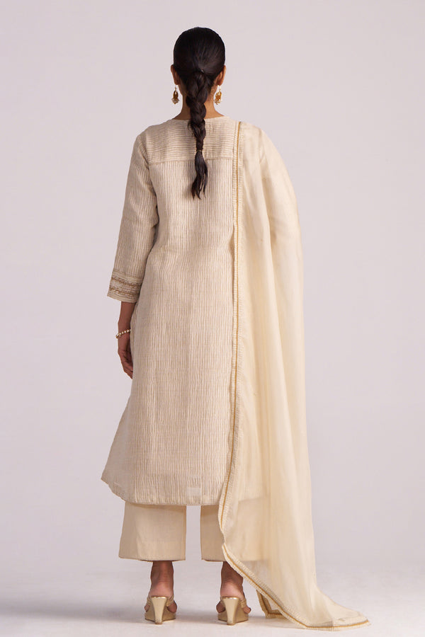 Woman wearing a Beige Woven Kurta Set with a dupatta on a plain background