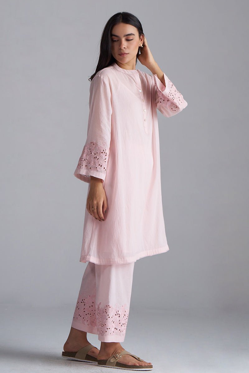 Woman wearing a light pink outfit with floral embroidery on a gray , Crystal Pink Mul Mul Co-ord Set for Women | Ganga Fashionsbackground