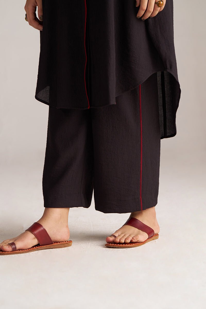 Person wearing black pants with red piping and brown sandals on a plain background, Black Co-ord Set for Women | Rangmanch Collection | Ganga Fashions
