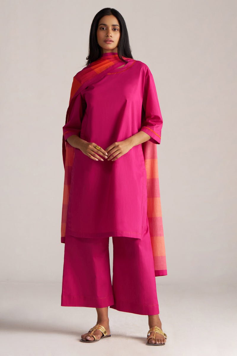 Woman wearing a bright pink traditional outfit with a matching dupatta on a plain background | Fuchsia Solid Kurta with Mul Mul Dupatta