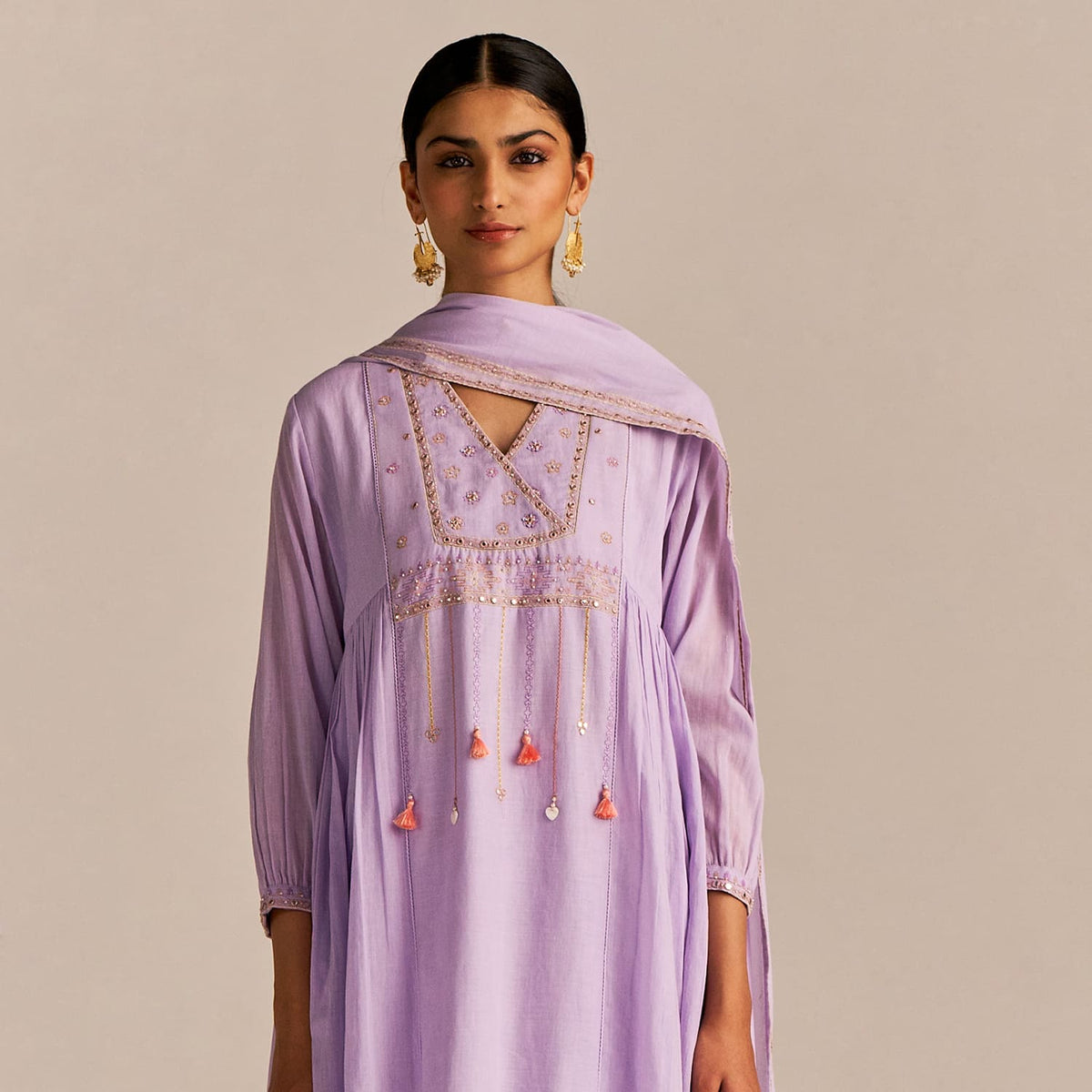 Woman wearing a light purple dress with intricate embroidery on a beige background | kahaniyaan collection by ganga fashions