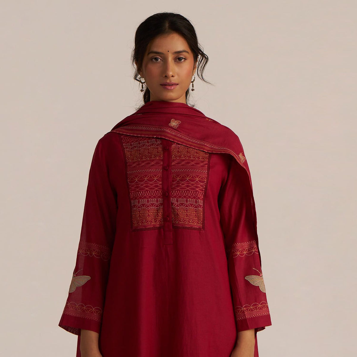 Woman wearing a red traditional outfit with intricate patterns on a plain background | ganga fashions by mogra collection